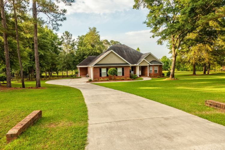 A concrete driveway leading to a residential home and yard by Sandee's Soil and Rock