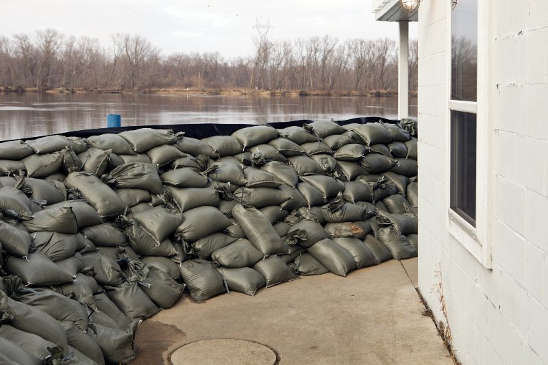 Sandbags forming a flood barrier beside a riverside building by Sandee’s Soil and Rock in Ogden, UT